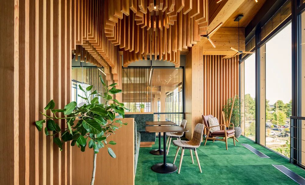 Mass timber is exposed in the material on the walls and ceiling of a room with tables and chairs.