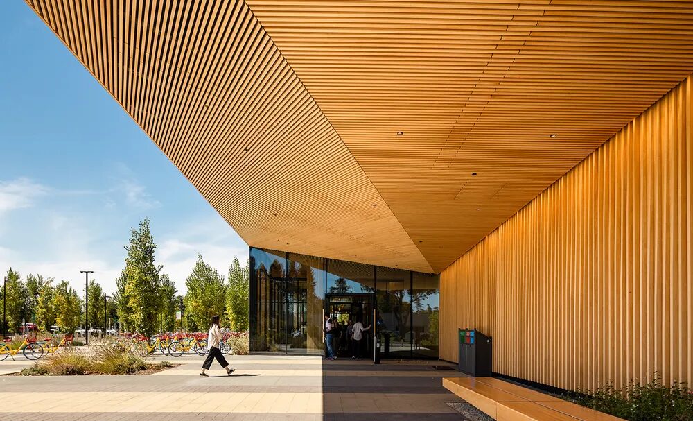 A person walks into a wooden building with a glass front entrance.