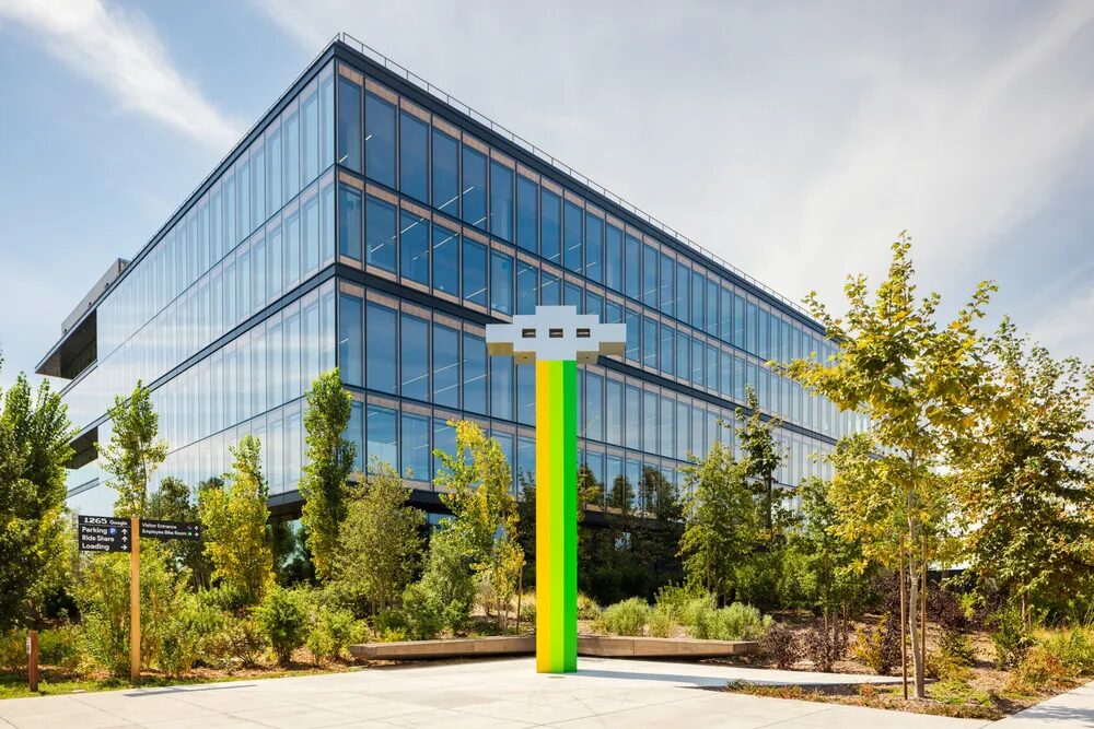 A large outdoor sculpture showcases a spaceship beaming down colors of green and yellow.